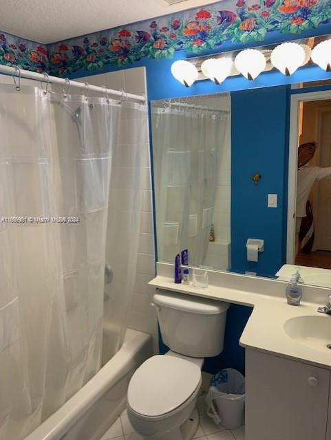 full bathroom featuring shower / bathtub combination with curtain, vanity, a textured ceiling, toilet, and tile patterned floors