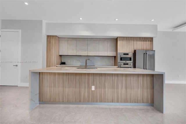 kitchen featuring backsplash, sink, a large island, and appliances with stainless steel finishes