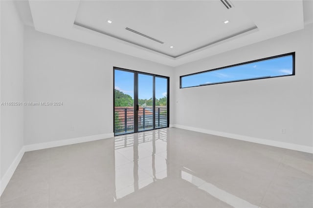 unfurnished room with light tile patterned floors and a raised ceiling