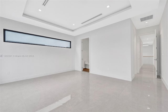 tiled empty room featuring a tray ceiling