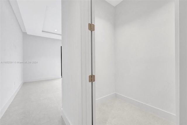 corridor featuring baseboards and light tile patterned flooring