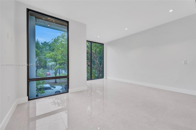 empty room featuring recessed lighting, baseboards, and expansive windows