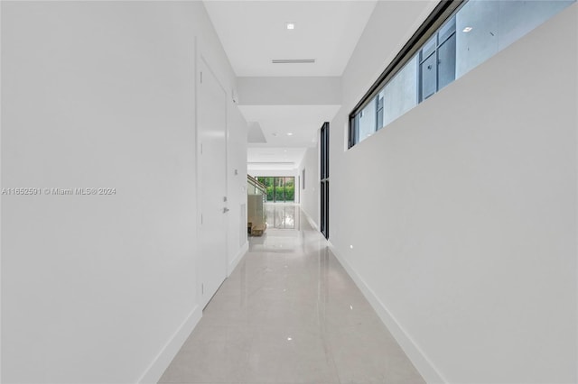 corridor featuring light tile patterned floors and baseboards