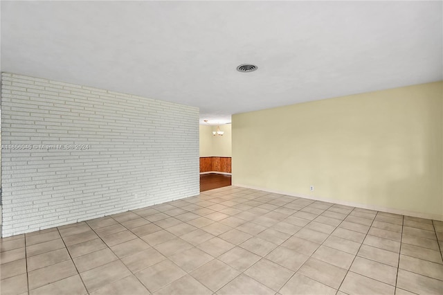 empty room featuring light tile patterned flooring and brick wall