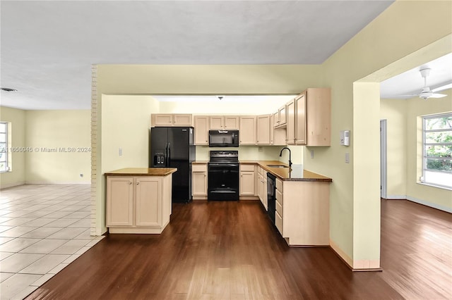 kitchen featuring black appliances, ceiling fan, dark hardwood / wood-style flooring, and sink