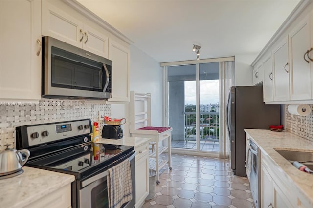 kitchen featuring floor to ceiling windows, stainless steel appliances, light stone counters, and backsplash