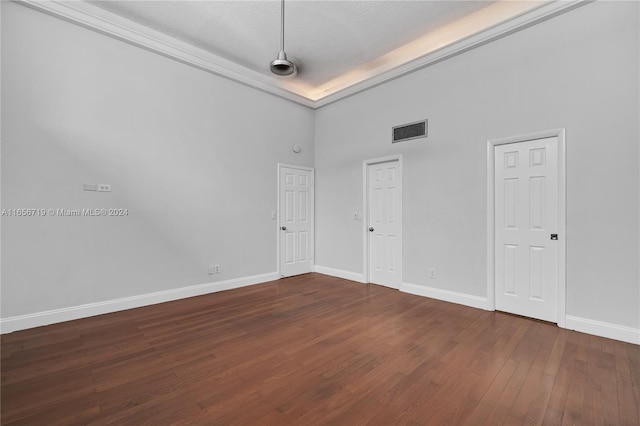 spare room with a textured ceiling, dark wood-type flooring, and a towering ceiling