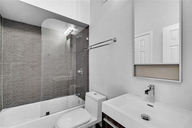 full bathroom with tiled shower / bath combo, vanity, and toilet