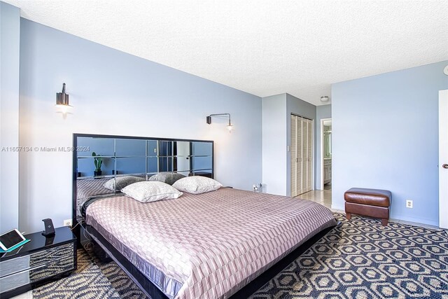 carpeted bedroom with a textured ceiling and a closet