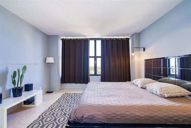 bedroom featuring a textured ceiling, light tile patterned floors, and multiple windows