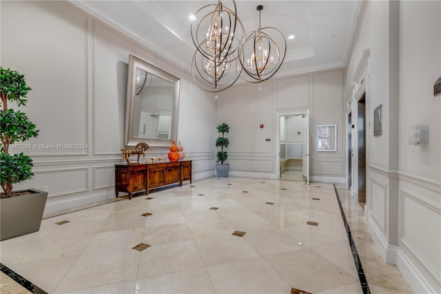 interior space featuring crown molding, a raised ceiling, and a notable chandelier