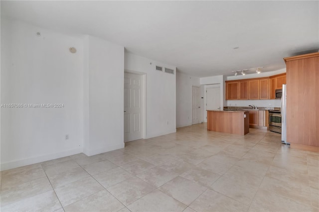 kitchen featuring appliances with stainless steel finishes, light tile patterned floors, a center island, and sink