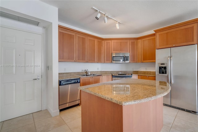 kitchen with a kitchen island, light stone counters, appliances with stainless steel finishes, and light tile patterned flooring