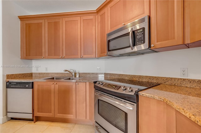 kitchen featuring light tile patterned floors, light stone counters, stainless steel appliances, and sink