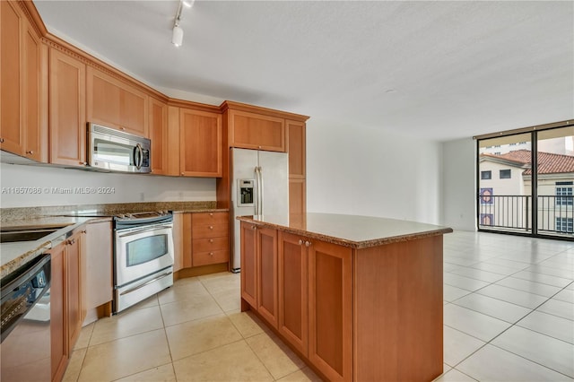 kitchen with a center island, stainless steel appliances, stone countertops, light tile patterned flooring, and floor to ceiling windows