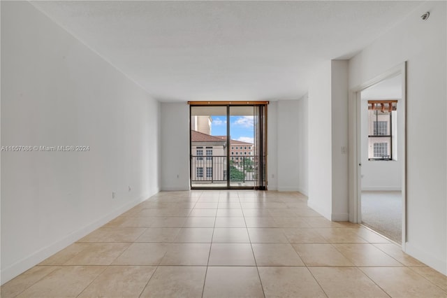 unfurnished room with light tile patterned floors and a wall of windows