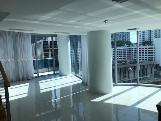 empty room with a wall of windows and tile patterned flooring