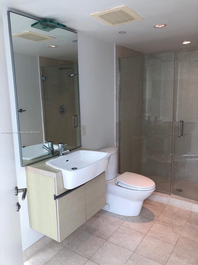 bathroom with a shower with door, vanity, toilet, and tile patterned flooring