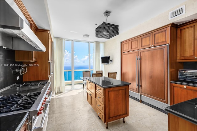 kitchen with range hood, a wall of windows, high quality appliances, a center island, and light tile patterned flooring