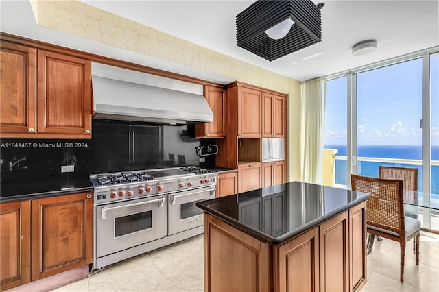 kitchen featuring double oven range, a water view, tasteful backsplash, a kitchen island, and extractor fan