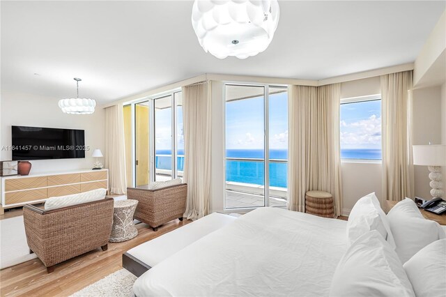 bedroom with access to outside, a water view, and hardwood / wood-style flooring