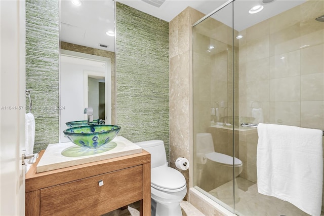 bathroom featuring vanity, a shower with shower door, tile walls, and toilet