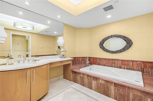 bathroom with tile patterned flooring, vanity, and tiled tub