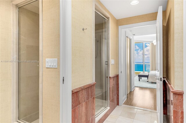 bathroom with hardwood / wood-style floors, a water view, and a shower with shower door