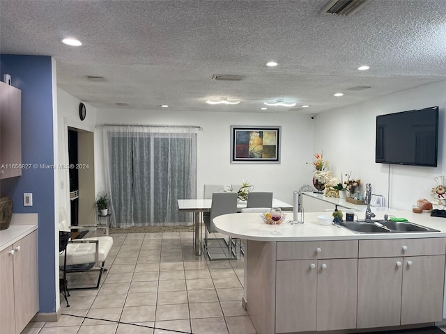 kitchen with a textured ceiling, light tile patterned floors, and sink