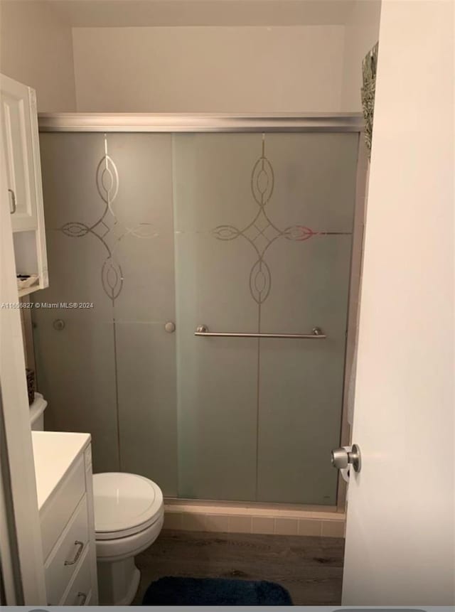 bathroom featuring an enclosed shower, wood-type flooring, toilet, and vanity