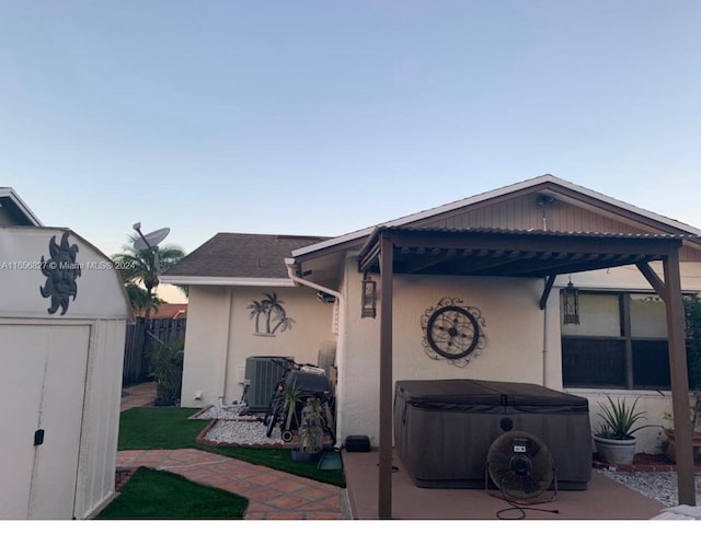 rear view of house with central AC unit, a storage unit, and a patio area