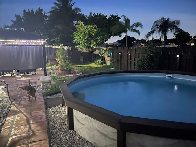 pool at dusk featuring a patio