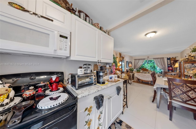 kitchen featuring light tile patterned floors, white cabinetry, stainless steel range with electric stovetop, and light stone counters