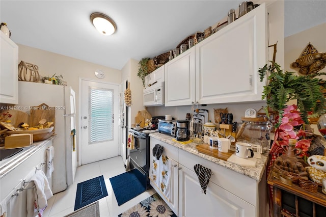 kitchen with white cabinets, light tile patterned flooring, light stone counters, and white appliances