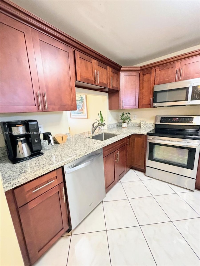 kitchen with light stone counters, sink, light tile patterned floors, and appliances with stainless steel finishes