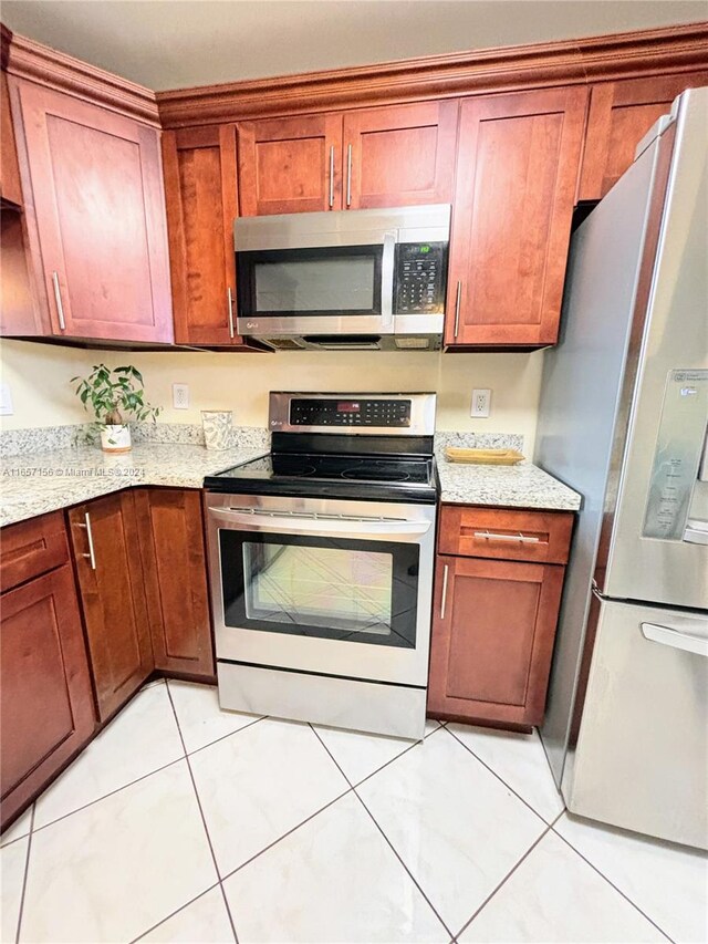 kitchen featuring stainless steel appliances, light stone countertops, and light tile patterned flooring