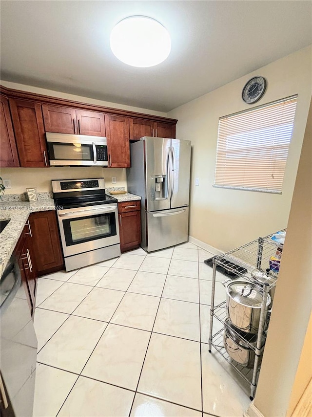 kitchen with stainless steel appliances, light stone counters, and light tile patterned floors