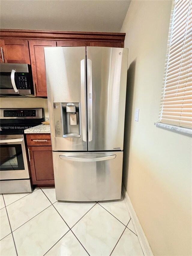 kitchen featuring light tile patterned floors, stainless steel appliances, and light stone countertops