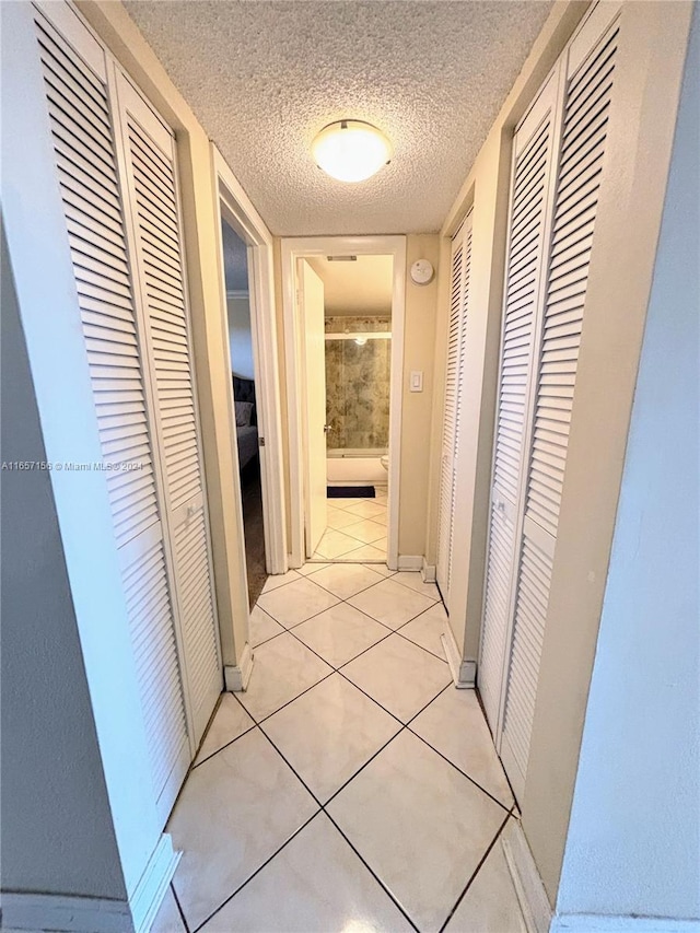 hall featuring a textured ceiling and light tile patterned floors