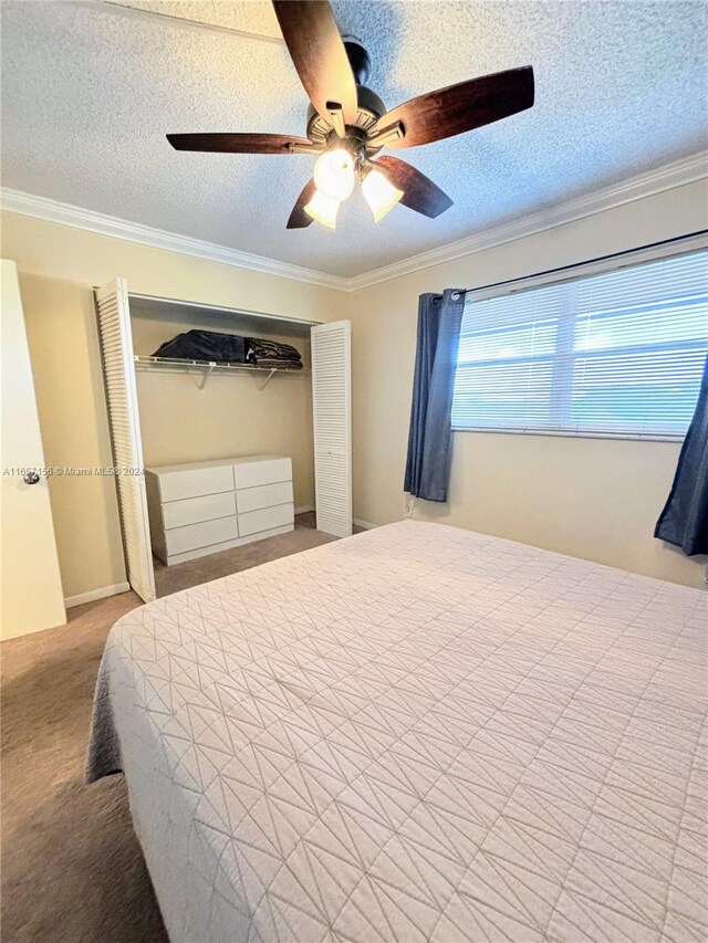 bedroom featuring ornamental molding, a textured ceiling, ceiling fan, a closet, and carpet floors