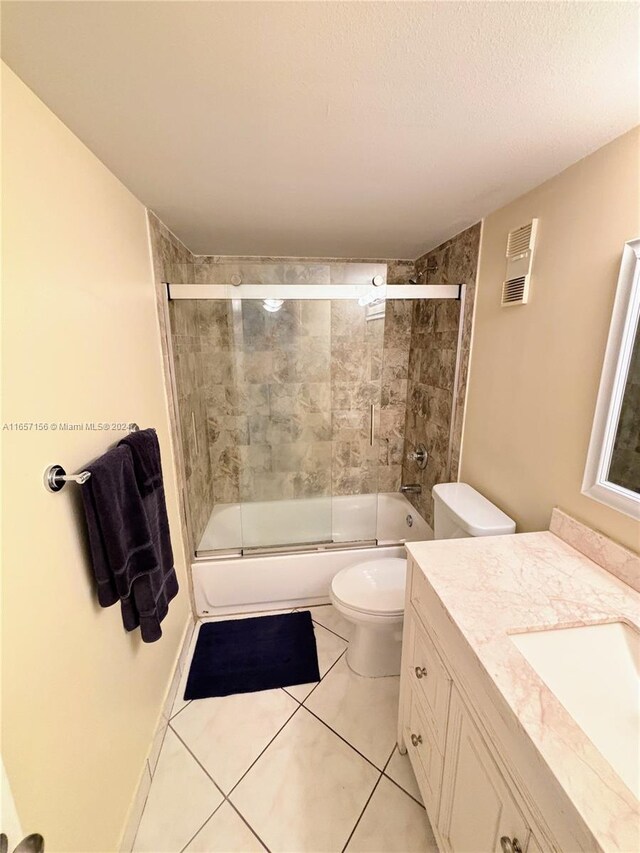 full bathroom with toilet, tile patterned flooring, shower / bath combination with glass door, vanity, and a textured ceiling