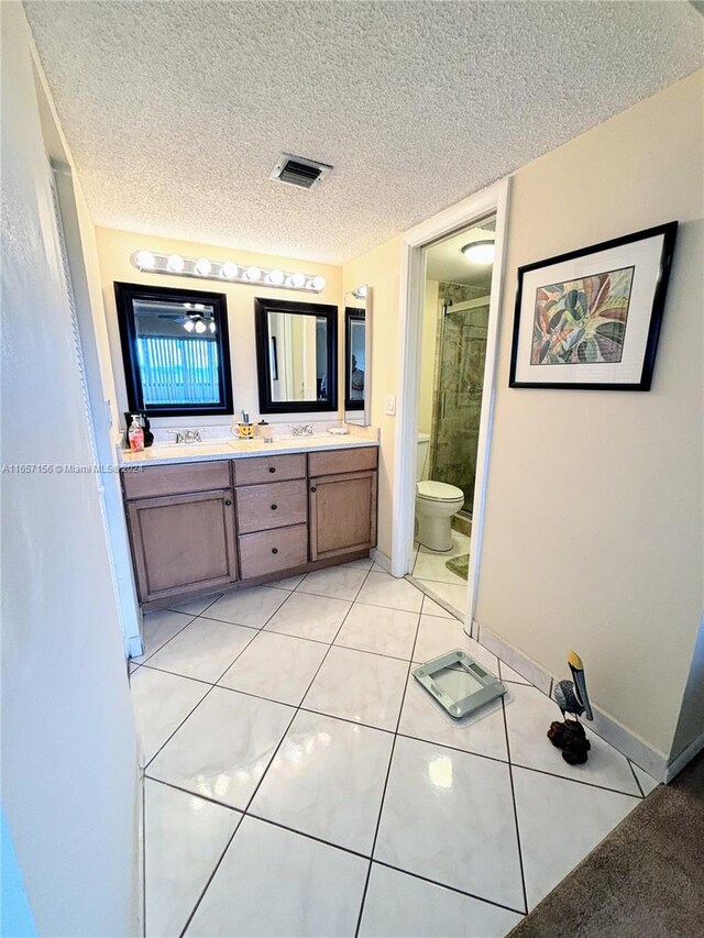 bathroom with toilet, walk in shower, tile patterned flooring, vanity, and a textured ceiling