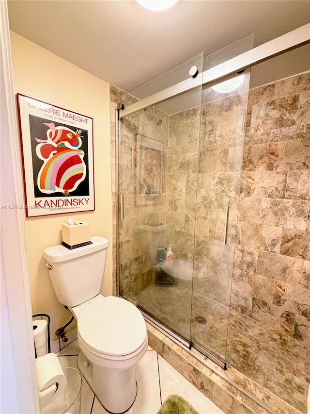 bathroom with toilet, tile patterned floors, and a shower with door