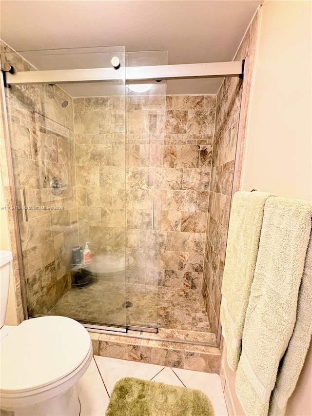 bathroom featuring toilet, an enclosed shower, and tile patterned floors