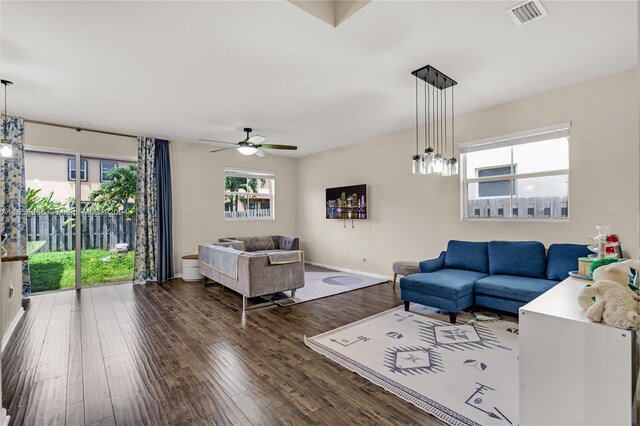 living room featuring ceiling fan with notable chandelier and dark hardwood / wood-style floors