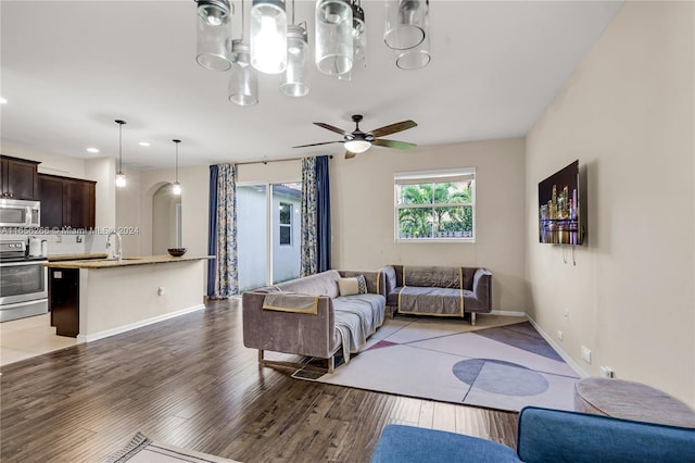 living room featuring sink, ceiling fan with notable chandelier, and light wood-type flooring