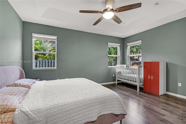 bedroom featuring a raised ceiling, ceiling fan, and dark hardwood / wood-style floors