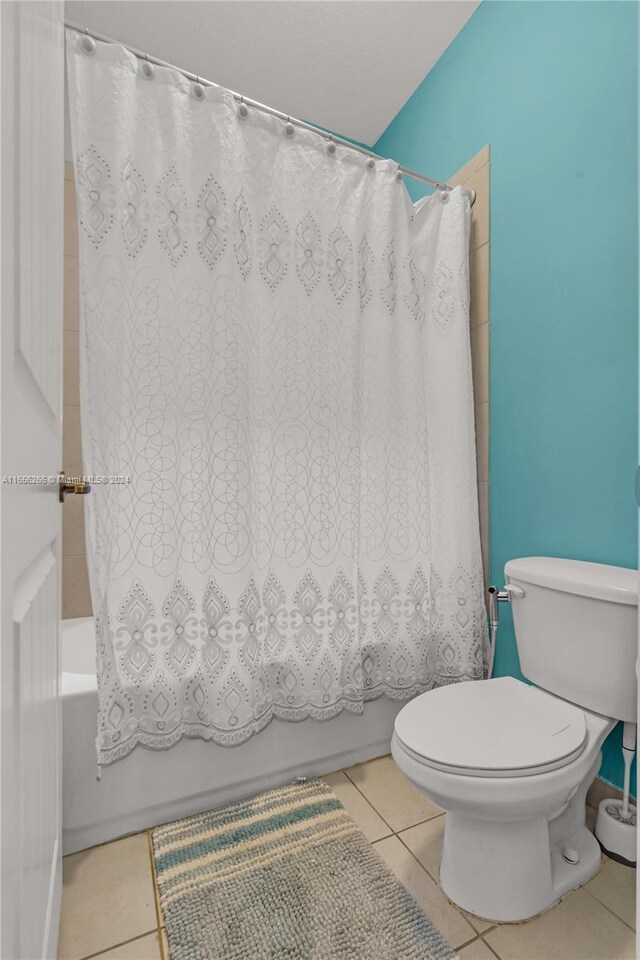 bathroom featuring tile patterned flooring, toilet, and shower / tub combo