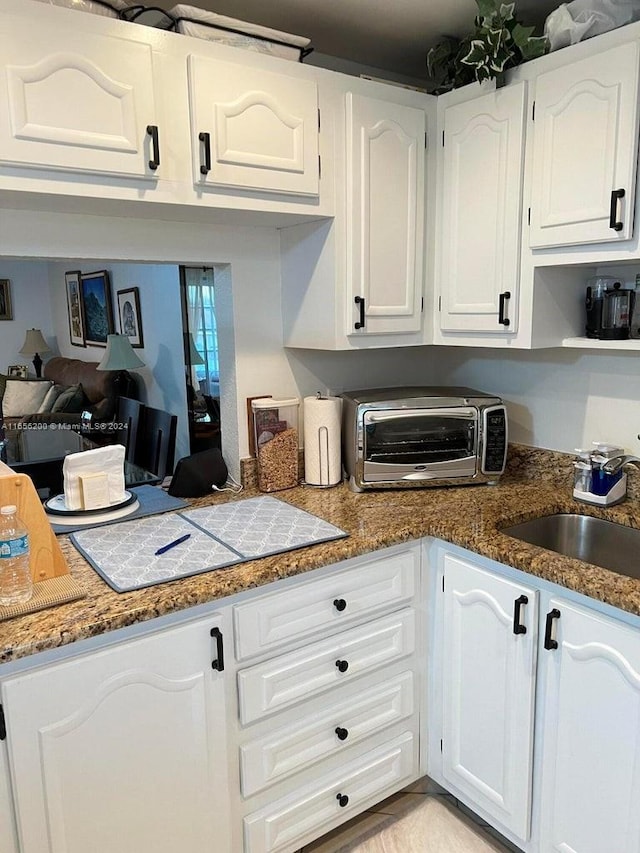 kitchen featuring dark stone countertops, sink, and white cabinets