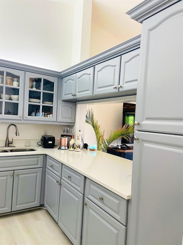 kitchen with light wood-type flooring, gray cabinetry, and sink